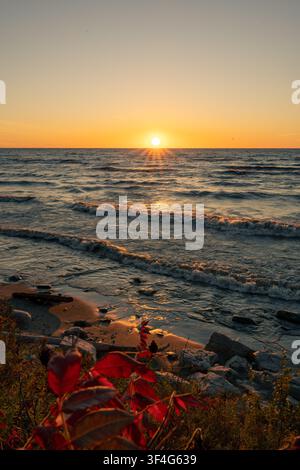 Sonnenaufgang über dem Ontariosee im East Point Park Bird Sanctuary in Toronto, Ontario, Kanada, mit Wellen, die das felsige Ufer erreichen. Stockfoto