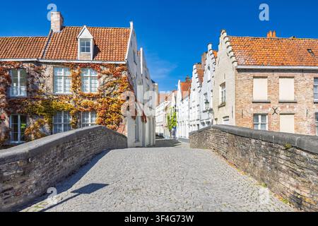Die Stadt Brügge in Belgien, Europa. Bezaubernde mittelalterliche Architektur mit lebhaftem Herbstlaub schmückt historische Kanalhäuser unter einem klaren blauen Himmel Stockfoto