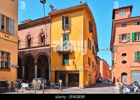 Bologna, Italien - Mai 2026: Farbige gelbe und terrakottafarbene historische Wohnhäuser an einer engen Straßenecke mit traditionellem Portikus Stockfoto
