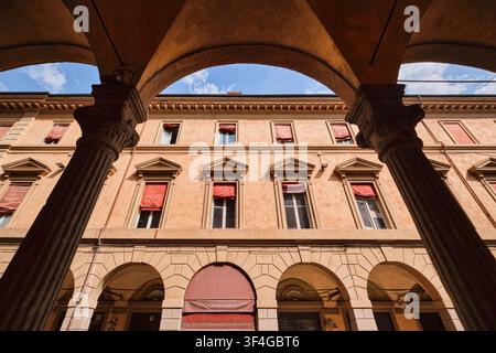 Bologna, Italien – Mai 2026: Blick aus niedriger Perspektive durch ein historisches gewölbtes Portal auf die Fassade eines klassischen Renaissance-Wohnhauses Stockfoto