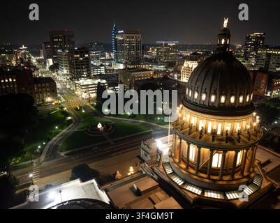 Große Kuppel des Boise Capitol Gebäudes leuchtet unter den Stadtlichtern bei Nacht. Hohe Gebäude beleuchten die Skyline der Innenstadt. Luftaufnahme, wie von einem Drone aus gesehen Stockfoto