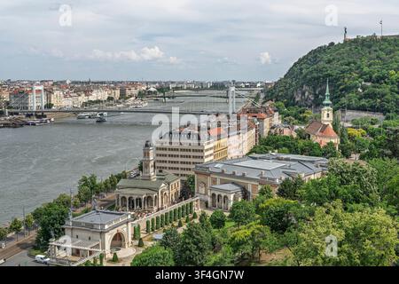 Von einer Terrasse des Budavarer Schlosses windet sich die Donau an bewaldetem Gellért-Hügel und Reihen historischer Ufergebäude vorbei, mit Kuppeln, Türmen und Booten sichtbar Stockfoto
