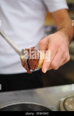Schöpfen von Schokoladeneis in eine Waffel Stockfoto