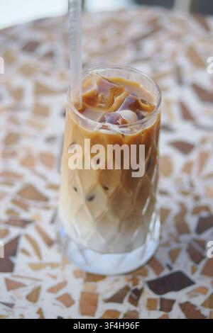 Eiskaffee-Getränk, das in einem hohen Glas auf einem Tisch serviert wird Stockfoto