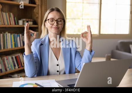 Geschäftsfrau meditiert am Arbeitsplatzschreibtisch mit Laptop Stockfoto