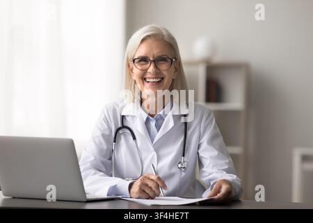 Porträt einer glücklichen, lächelnden, älteren Ärztin bei der täglichen Arbeit Stockfoto