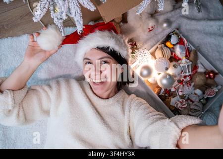 Frau in Santa hat genießt Weihnachten unter dem Baum Stockfoto