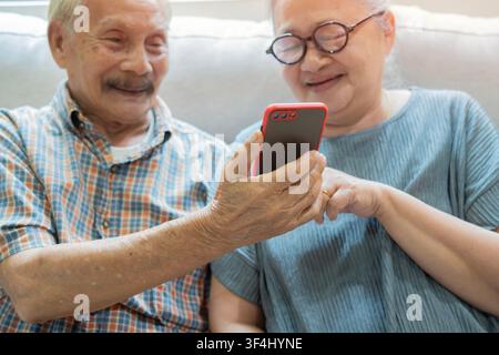 Smartphone-Nutzung bei älteren Erwachsenen, glückliches Seniorenehepaar lernt die Interaktion mit telefonischen digitalen Informationen online. Selektiver Fokus. Stockfoto