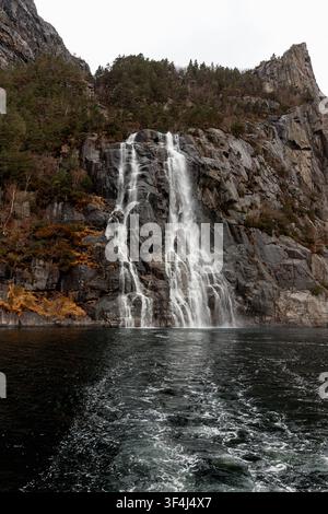 Ein spektakulärer Blick auf den Hengjanefossen-Wasserfall, der über steile Granitklippen in die Gewässer des Lysefjords in Norwegen stürzt Stockfoto
