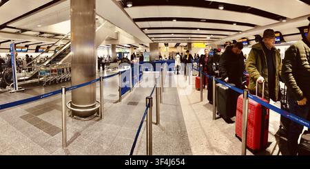 Passagiere stehen mit Gepäck an einer Sicherheitskontrolle am Flughafen mit Barrieren, Heathrow Airport, London, UK Stockfoto