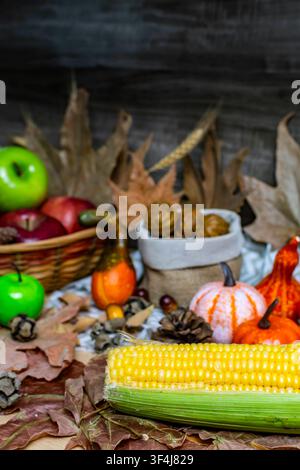 Herbststilleben mit verschiedenen geernteten Früchten und Kürbissen sowie getrockneten Blättern Stockfoto