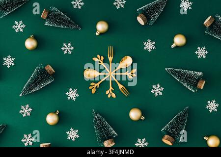 Kreatives Wintermuster mit goldenem Besteck-Schneeflocke, Weihnachtsbäumen, goldenen Verzierungen und dekorativen Schneeflocken auf grünem Hintergrund. Stockfoto