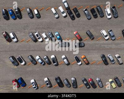 Luftbild von oben von Autos, die in Reihen auf einem großen Außenparkplatz geparkt sind, Konzept für urbane Verkehrsanlagen und Fahrzeuglagerung. Stockfoto