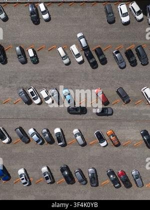 Luftbild von oben von Autos, die in Reihen auf einem großen Außenparkplatz geparkt sind, Konzept für urbane Verkehrsanlagen und Fahrzeuglagerung. Stockfoto