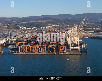 Luftbild eines modernen Containerhafens mit Ladekränen, gestapelten Frachtcontainern und Frachtschiff, das den internationalen Handel zeigt und Stockfoto