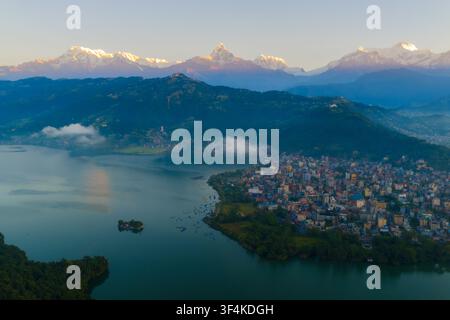 Luftaufnahme des Phewa-Sees und der Stadt Pokhara, die sich unter den schneebedeckten Gipfeln der Annapurna-Bergkette in Nepal befindet. Stockfoto
