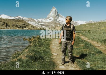 Mann wandert auf Bergpfad und sieht Reflexionen auf dem Seewasser Stockfoto