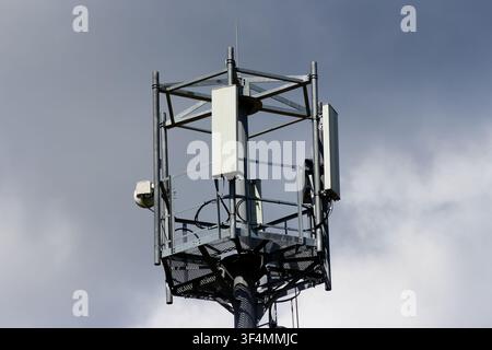 Stahl-Zellular-Kommunikationsturm mit Paneantennen vor einem wolkigen Himmelshintergrund, professionelle Industrieausrüstung für drahtlose Netzwerkverbindung Stockfoto