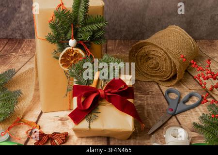 Handgemachte Feiertagsgeschenke mit natürlichen Dekorationen und gemütlichen Verpackungsmaterialien auf Holzoberfläche Stockfoto
