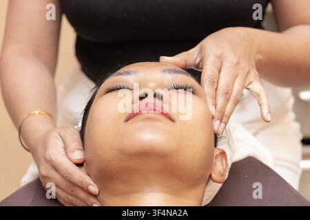 Junge asiatische Frau erhält entspannende Thai-Gesichtsmassage in einem Spa-Salon Stockfoto