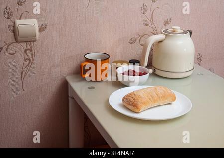 Einfache Frühstückseinrichtung mit Brot, Beeren und einer Tasse auf einem Glastisch Stockfoto