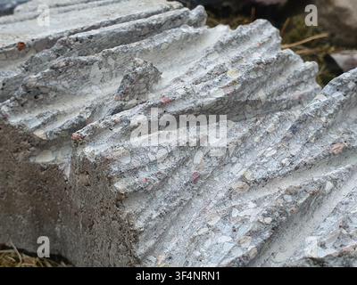 Nahaufnahme von gestapelten Betonbausteinen mit ausgeprägten gerippten oder welligen Texturen. Die graue Zementoberfläche zeigt freiliegendes Stockfoto