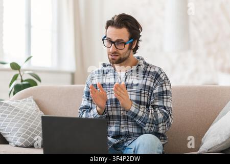Konzentrierter kaukasischer Mann arbeitet an einem Laptop während einer Videokonferenz zu Hause, Geschäftskonzept Stockfoto