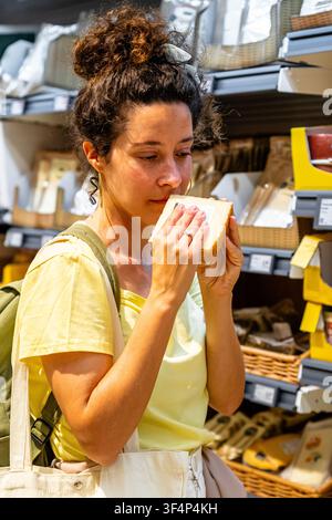 Frau riecht einen Käseblock beim Kauf von Lebensmitteln im Supermarkt Stockfoto