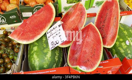 MILAN, ITALIEN - 15. JUNI 2024: Halbiertes und in Scheiben geschnittenes frisches rotes Wassermelone, in Klarsichtfolie eingewickelt, mit einem Preisschild, das auf einem Obstmarkt in Mailand ausgestellt ist, Ital Stockfoto