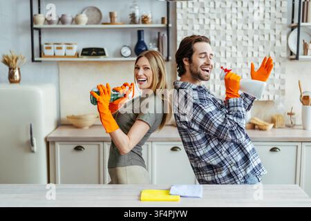 Glücklicher kaukasischer Mann und Frau putzen zusammen in der Küche, lächeln, Konzept für Hausarbeit Stockfoto