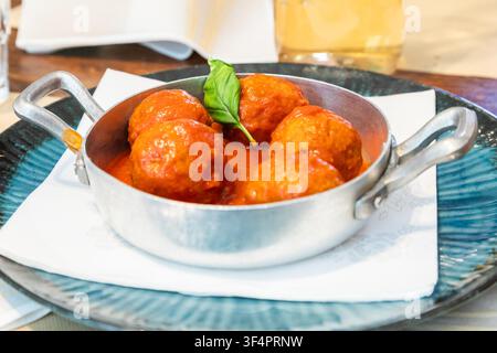 Traditionelle Fleischbällchen serviert mit Basilikumblatt und Tomatensauce. Italienisches Restaurant Osteria in Turin, Norditalien. Stockfoto