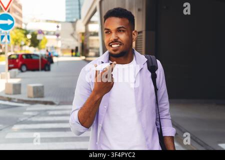 Junger afroamerikanischer Mann spricht am Smartphone, während er in der Stadt läuft, Geschäftskonzept Stockfoto