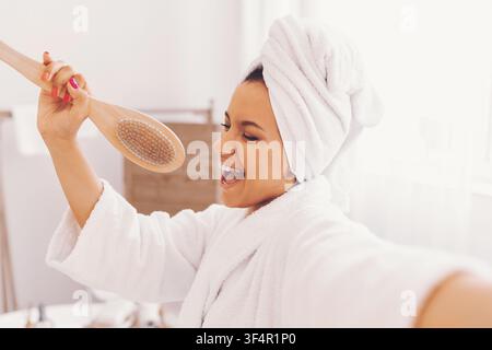 Glückliche junge Frau genießt ihre Badezeit, singt im Badezimmer, Gewichtsabnahme-Konzept Stockfoto