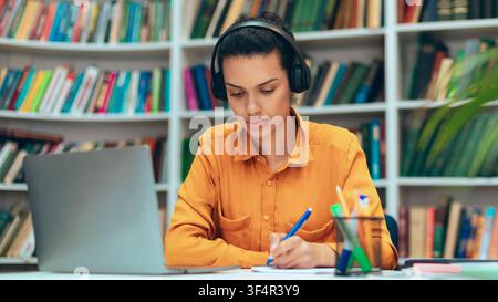 Konzentrierte junge afroamerikanische Frau studiert mit Laptop und Kopfhörern, Home-Office-Konzept Stockfoto