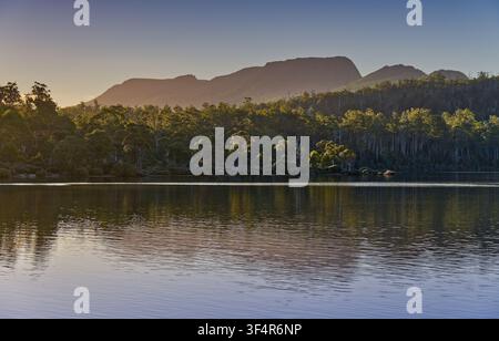 Ein Gebirgszug spiegelt sich im Wasser des Lake St Clair im späten Nachmittagslicht wider, Tasmanien, Australien Stockfoto