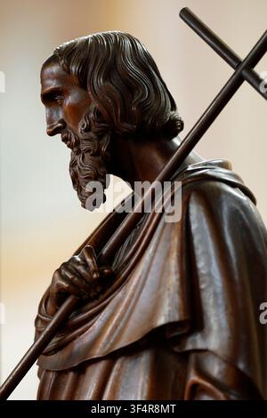 Kollegiatkirche Saint-Jacques. Eine geschnitzte Holzstatue, die einen bärtigen Heiligen oder Apostel darstellt, der ein Kreuz trägt, im linken Profilansicht. Stockfoto