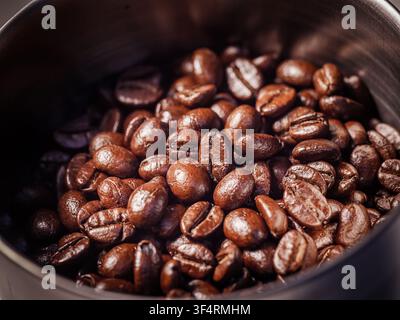 Nahaufnahme von frisch gerösteten Kaffeebohnen in einem Kaffeemühltrog. Reiche Textur und Aroma für das Espresso-Konzept Stockfoto