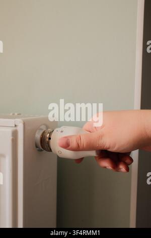 Nahaufnahme einer Hand, die einen Heimheizkörperthermostat einstellt. Heizungsregelung, Energieeffizienz und Raumtemperaturmanagement in einer modernen Wohnung. Stockfoto
