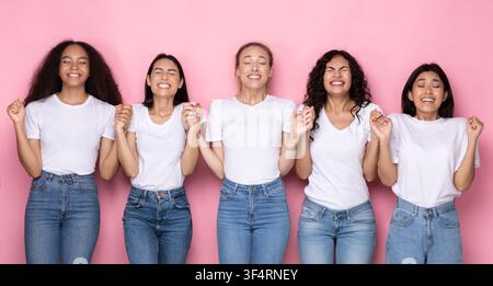 Multiethnische Frauen Machen Wunsch Halten Hände Stehen Über Rosa Hintergrund Stockfoto