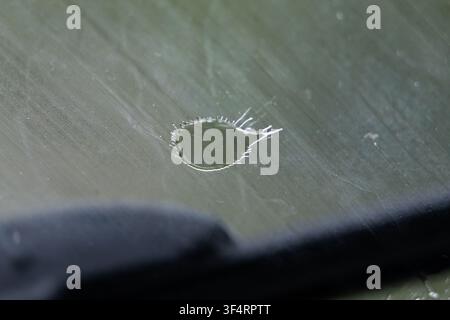 Ein Tränenring markiert das Glas, während eine dunkle Wischerkante das Bild durchquert. Kratzer und weiches grünes Licht vervollständigen die Szene. Die ruhige Komposition su Stockfoto