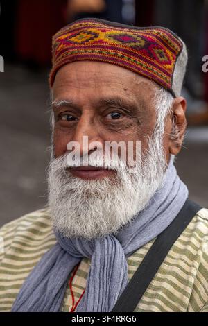Porträt eines älteren Mannes mit Bart, einem farbenfrohen traditionellen Hut und einem grauen Schal in Dharamsala, Himachal Pradesh, Indien. Stockfoto