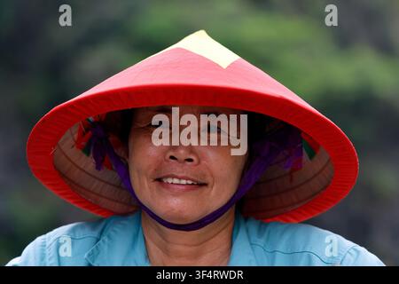 Hoa Lu, Vietnam. Eine lächelnde Frau trägt einen traditionellen vietnamesischen Kegelhut. Stockfoto