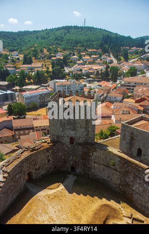 Hochwinkelaufnahme eines historischen Steinturms mit Ziegeldach und Wallgang am Schloss Montalegre, mit Blick auf die Stadthäuser. Stockfoto