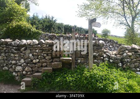 Holztorpfosten mit Steintritten in einer Trockenmauer am Dales Way-Fußweg zwischen Burnsall & Grassington, Wharfedale, Yorkshire Dales, England, UK. Stockfoto