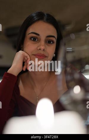 Junge Frau posiert während eines romantischen Abendessens und genießt einen entspannten und eleganten Moment Stockfoto
