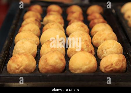 Eine Nahaufnahme von frisch zubereitetem Takoyaki, dem berühmten japanischen Straßenessen. Die runden Bällchen haben eine goldbraun knusprige Außenseite, die perfekt zur Schau gestellt wird Stockfoto