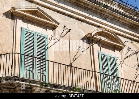 Steinfassade mit 2 Balkonen, grünen Fensterläden und dekorativen Eisenkonsolen, Ragusa Ibla, Sizilien, Italien Stockfoto