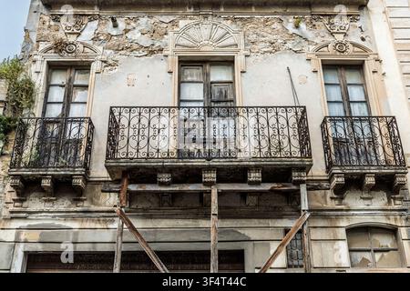Verwitterte historische Fassade mit hölzernen Stützen für ihre alternden Balkone, Noto, Sizilien, Italien Stockfoto