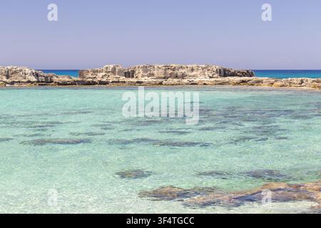 Kristallklares türkisfarbenes Wasser in einer ruhigen mediterranen Bucht mit Felsformationen und Riff, das unter der ruhigen Meeresoberfläche sichtbar ist. Strand von Ayfilon Karpaz Stockfoto