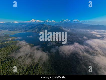 Luftaufnahme des Phewa-Sees und der Stadt Pokhara, die sich unter den schneebedeckten Gipfeln der Annapurna-Bergkette unter einem klaren blauen Himmel befindet, Nepal. Stockfoto